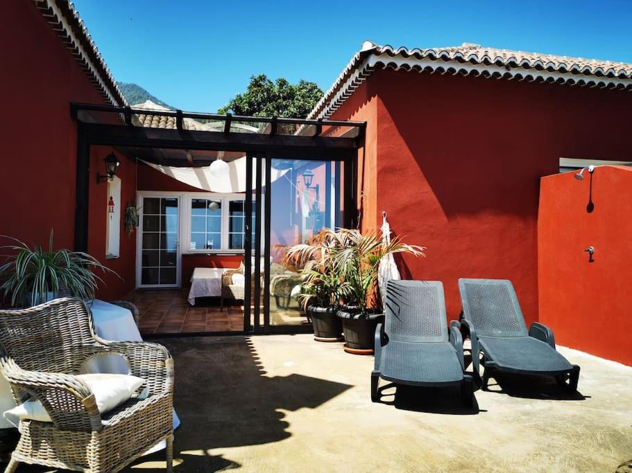 a patio with wicker chairs and a red house at CASA ISA, ideal para descansar. in Santa Cruz de la Palma