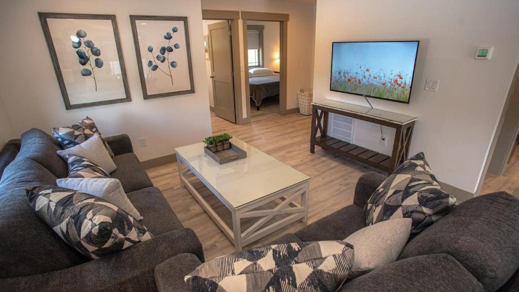 a living room with two couches and a flat screen tv at The Raspberry Garden Luxury Hotel & Suites in Rexburg