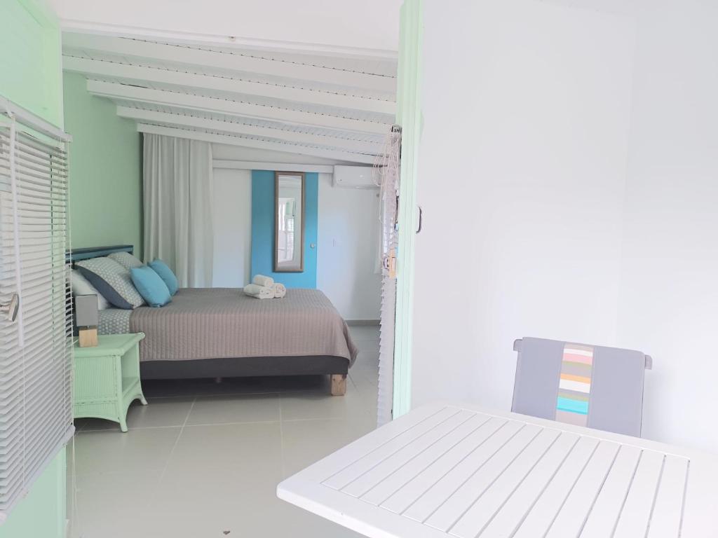 a bedroom with a bed in a white room at La Rose du Bresil Marie-Galante in Capesterre