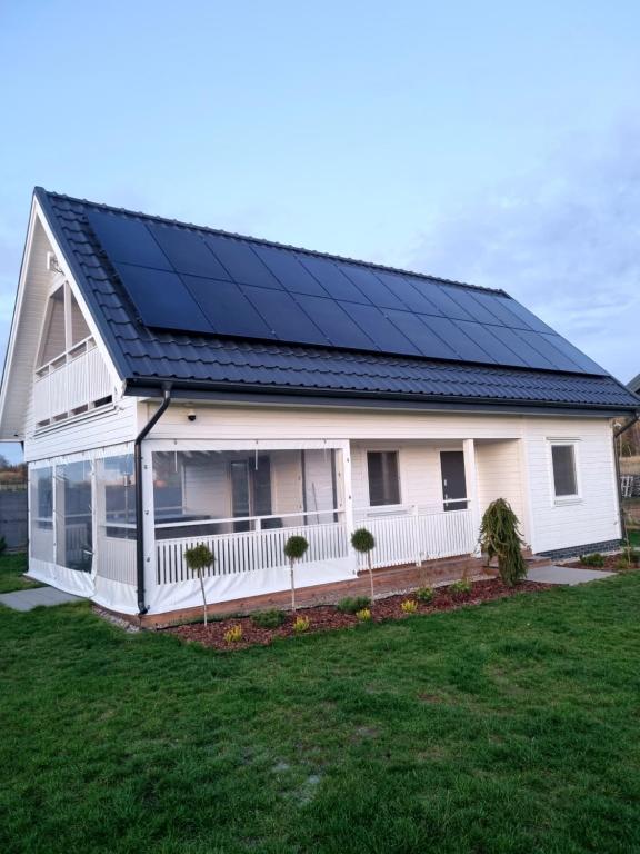 una casa con paneles solares en el techo en Fuledzki Biały Domek - Mazury, Jacuzzi, Sauna, Giżycko, en Fuleda