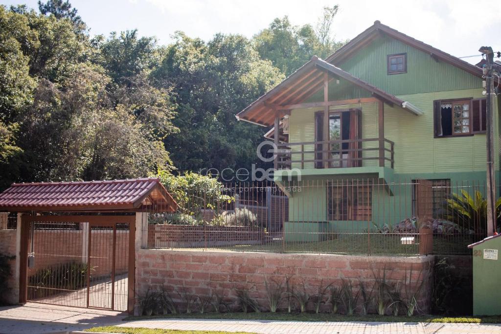 una casa verde con una puerta y una valla en Casa Completa - Nova Petrópolis, en Nova Petrópolis