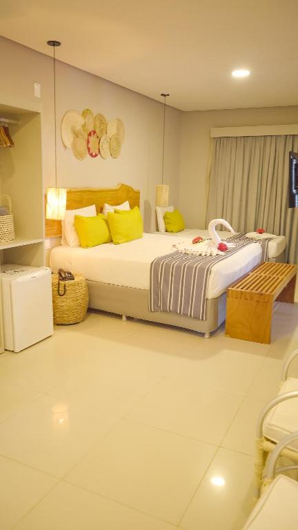 a bedroom with two beds with yellow pillows at Baía Branca Beach Resort in Tamandaré