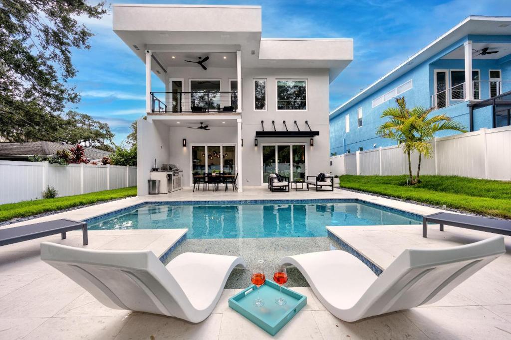 uma casa com piscina e duas cadeiras brancas em #4 Tropical Paradise with Saltwater Heated Pool 10 min to Siesta Key Beach em Sarasota