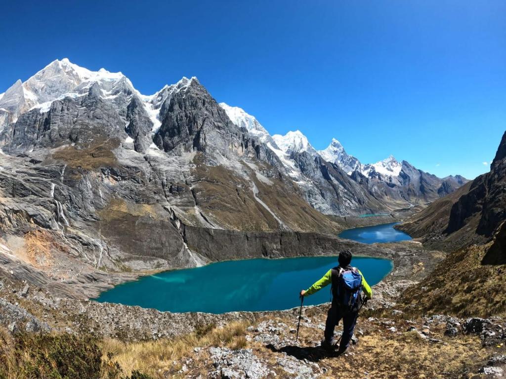 a man standing on a mountain looking at a mountain lake at Humberto Guest House in Huaraz