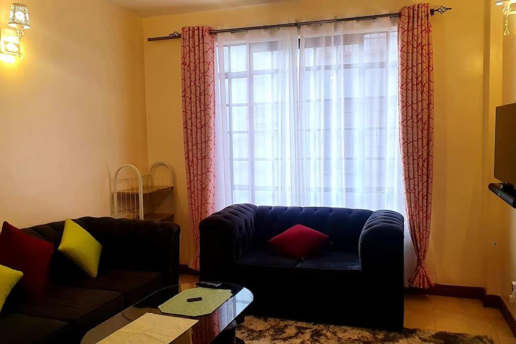 a living room with a couch and a window at Spacious 2bedroom condo w free parking on premises in Nairobi