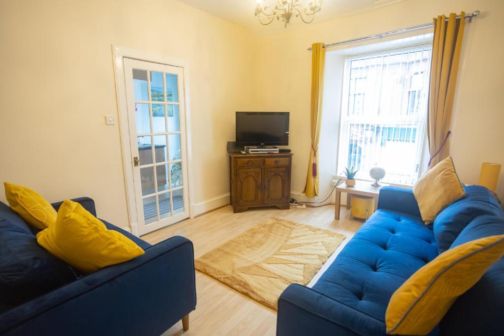 a living room with two blue couches and a television at Sandgate 2-Bed Apartment in Ayr central location in Ayr