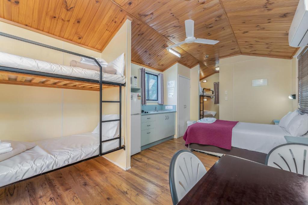 a room with two bunk beds and a dining table at BIG4 Lake Maraboon Holiday Village in Gindie