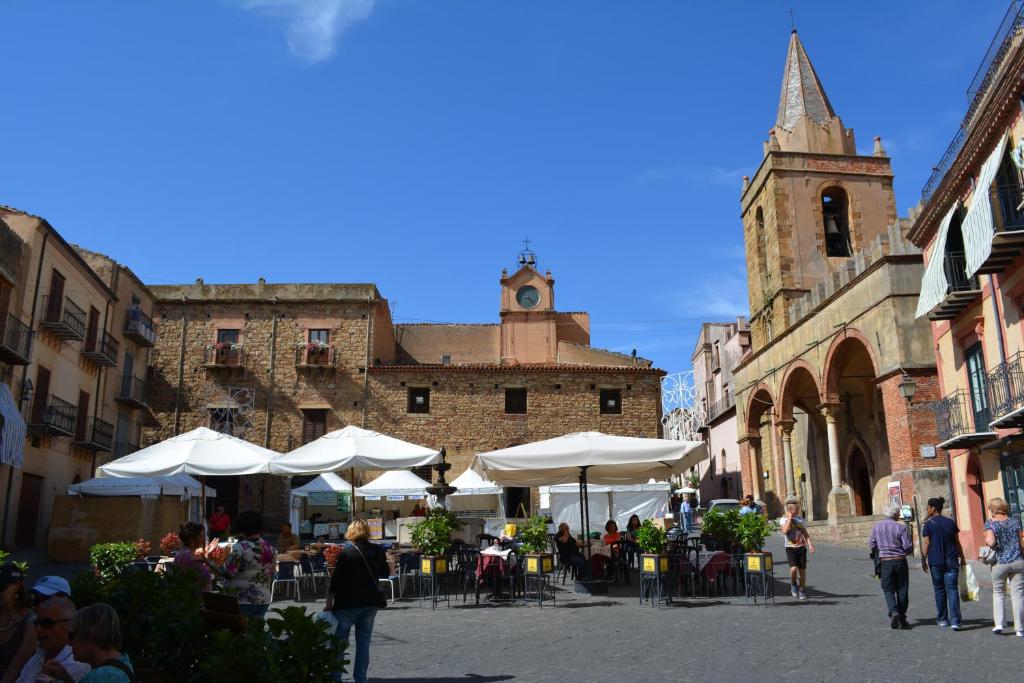 una calle con mesas y sombrillas y una iglesia en The House of Castle Apartments, en Castelbuono