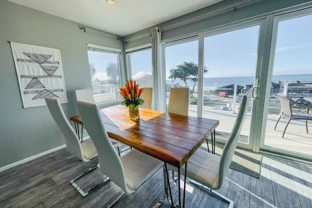 een eetkamer met een tafel en stoelen en de oceaan bij Pier View Suites - Townhouse A in Cayucos