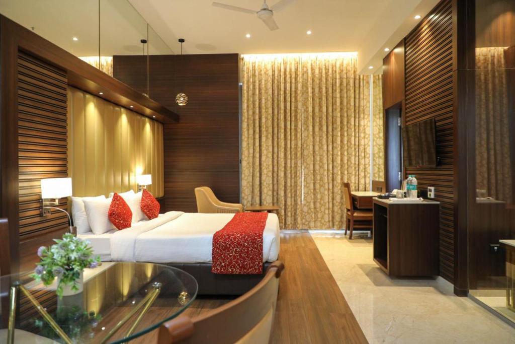 a hotel room with a bed and a dining room at Hotel Gurudev Grand in Kalyan