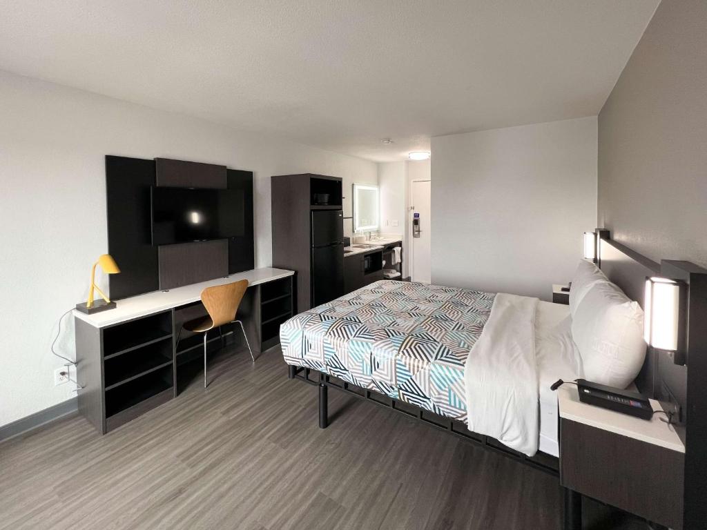 a hotel room with a bed and a desk and a computer at Studio 6 Altoona IA Des Moines East in Altoona