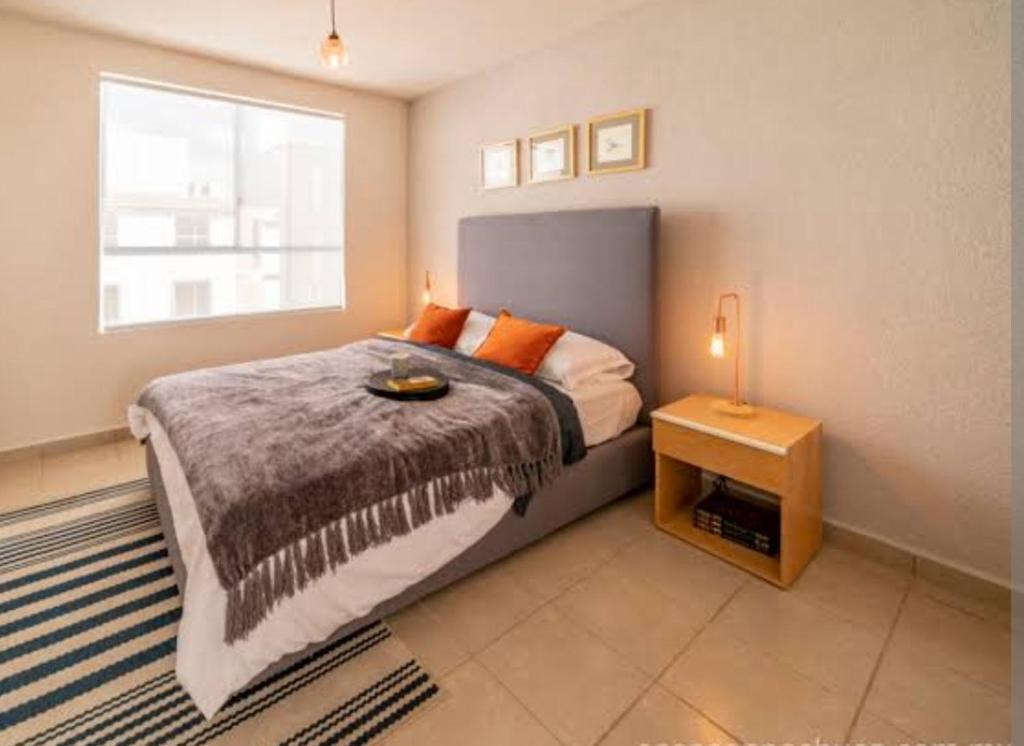 1 dormitorio con 1 cama con almohadas de color naranja y ventana en Casa san jose, en Chicoloapan de Juárez