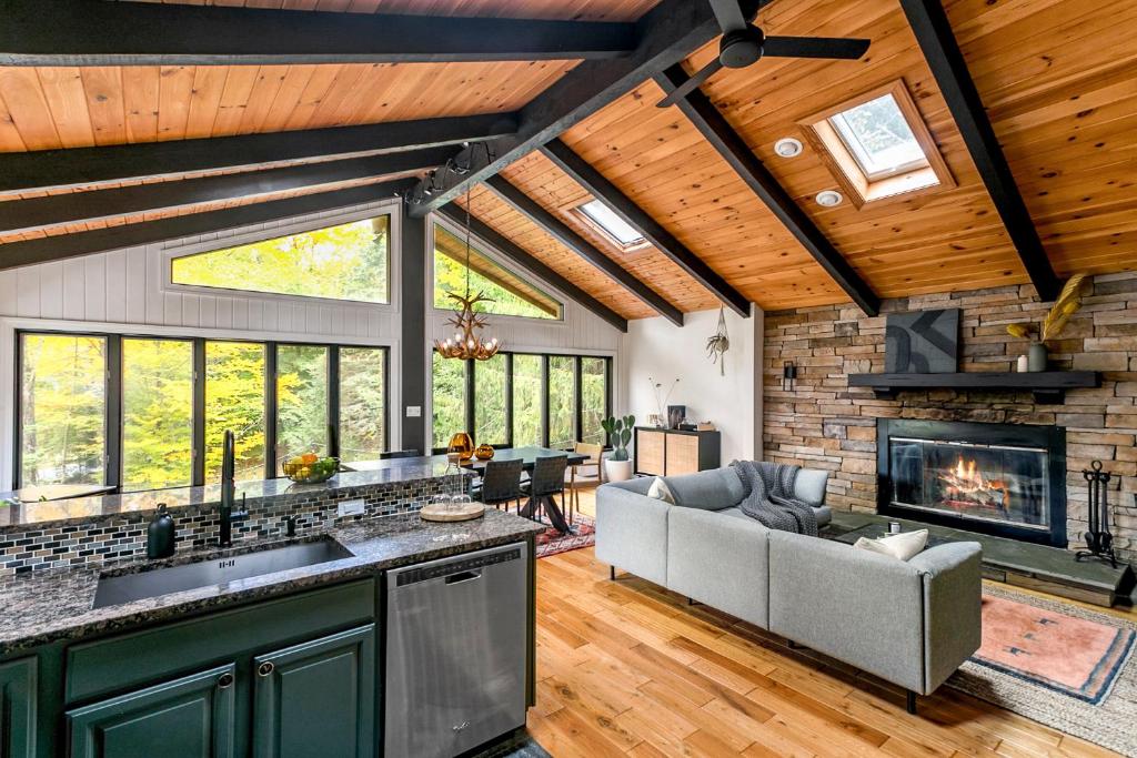 a kitchen and living room with a couch and a fireplace at Woodpecker House - Mountain retreat with hot tub - 10 min to skiing in Hunter & Windham in Jewett