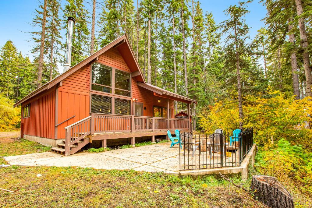 a red cabin in the woods with a deck and chairs at Peak-a-View Lakehouse in Ronald