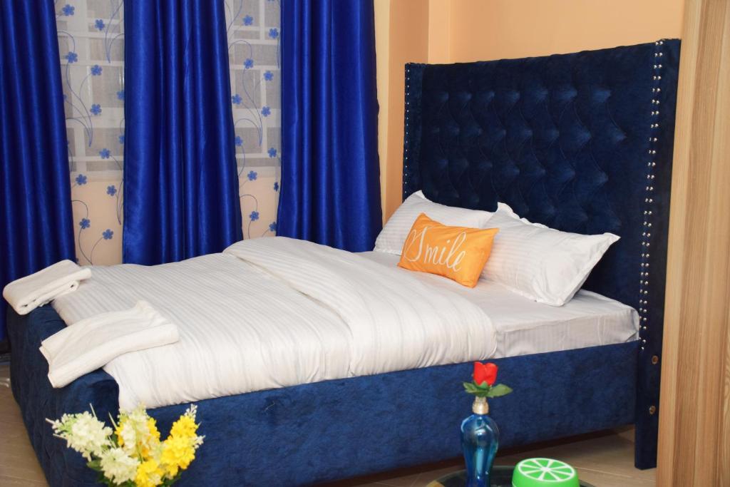 un letto con testiera blu e tende blu di Soft home studio a Nairobi