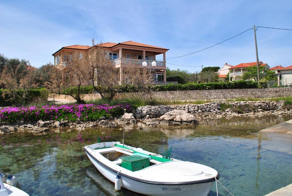 een boot in het water voor een huis bij Seaside apartments with a swimming pool Ugljan - 829 in Ugljan