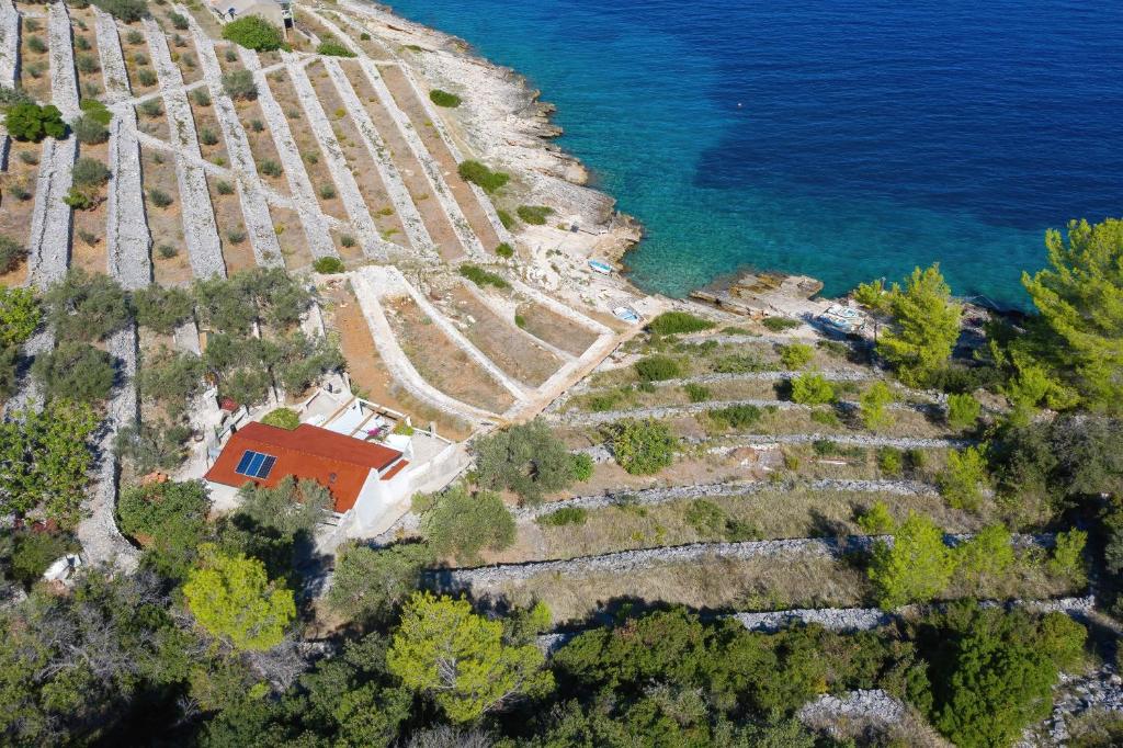 an aerial view of a house on a hill next to the water at Secluded fisherman's cottage Cove Stiniva, Korcula - 11389 in Vela Luka