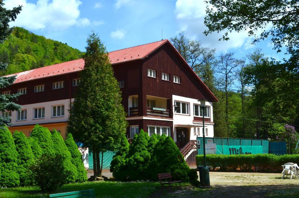 a large brown building with a red roof at Sport Hotel Gejzirpark in Karlovy Vary