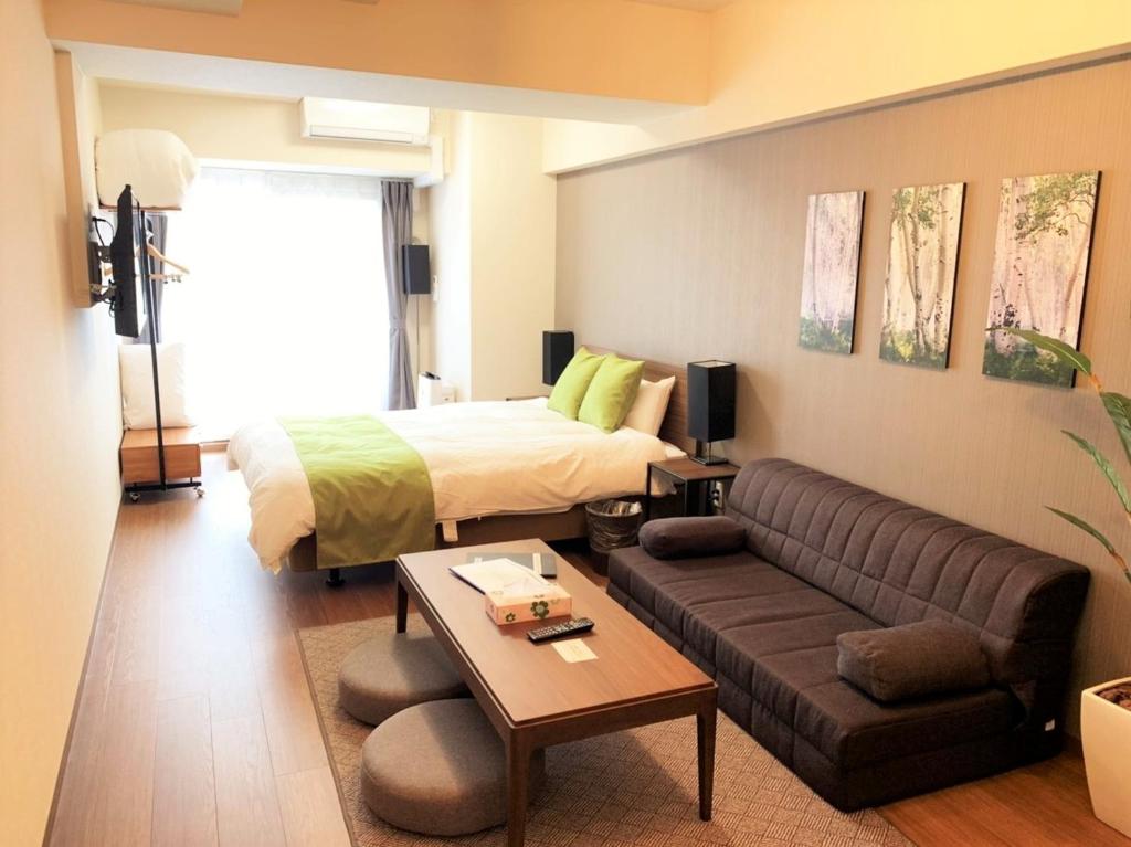 een hotelkamer met een bed en een bank bij RLiS-house Shin-Osaka Kita - Vacation STAY 9529 in Osaka