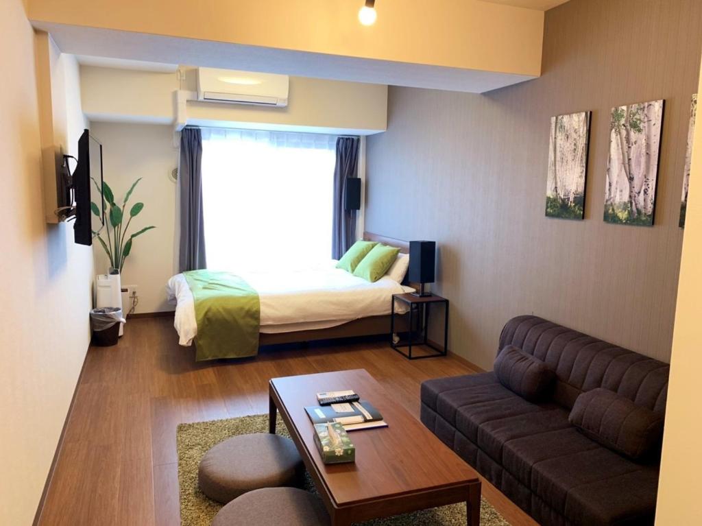 een woonkamer met een bank en een bed bij RLiS-house Shin-Osaka Kita - Vacation STAY 9525 in Osaka