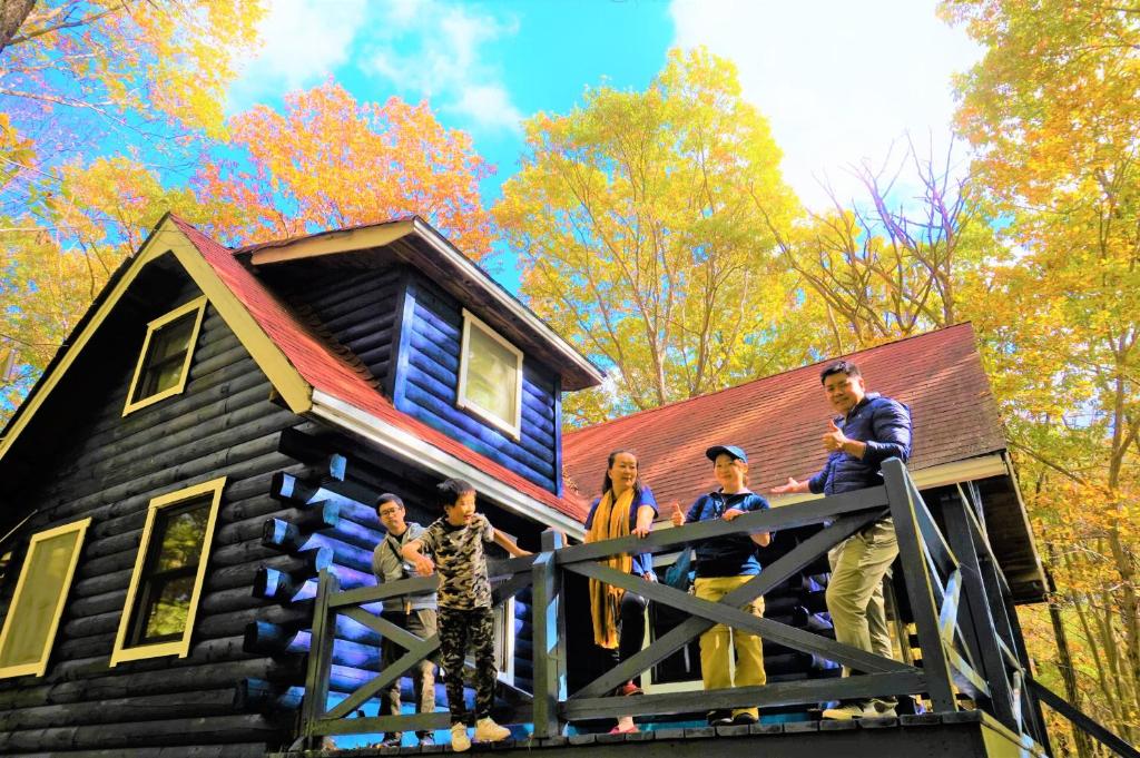 a group of people standing on the porch of a log cabin at 【那須高原の自然に囲まれたログハウス1棟貸し】ファミリー利用、大人数での利用、パーティも大歓迎！ in Nasu-yumoto