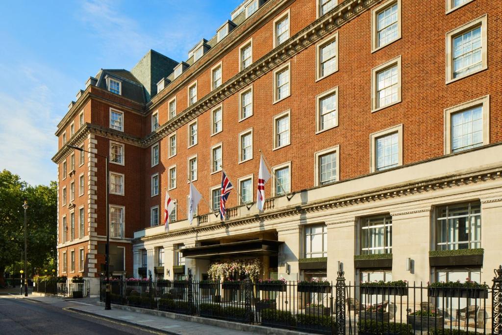 un grande edificio in mattoni rossi con bandiere di London Marriott Hotel Grosvenor Square a Londra