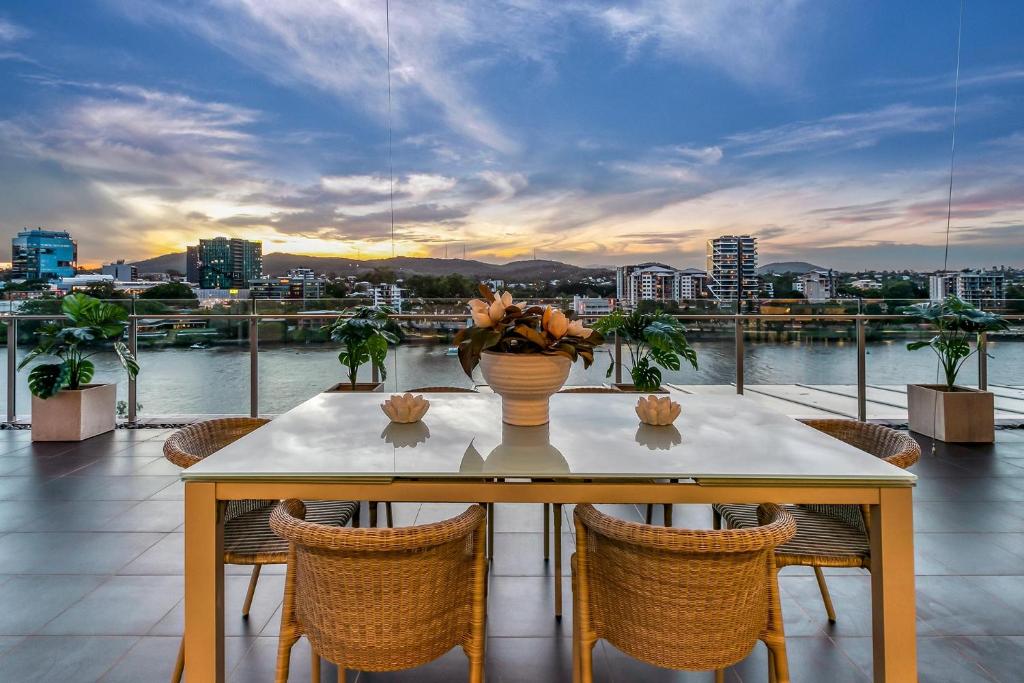 a table and chairs on a balcony with a view of a city at Stunning Waterfront Penthouse 3 or 4 Bedrooms in Brisbane