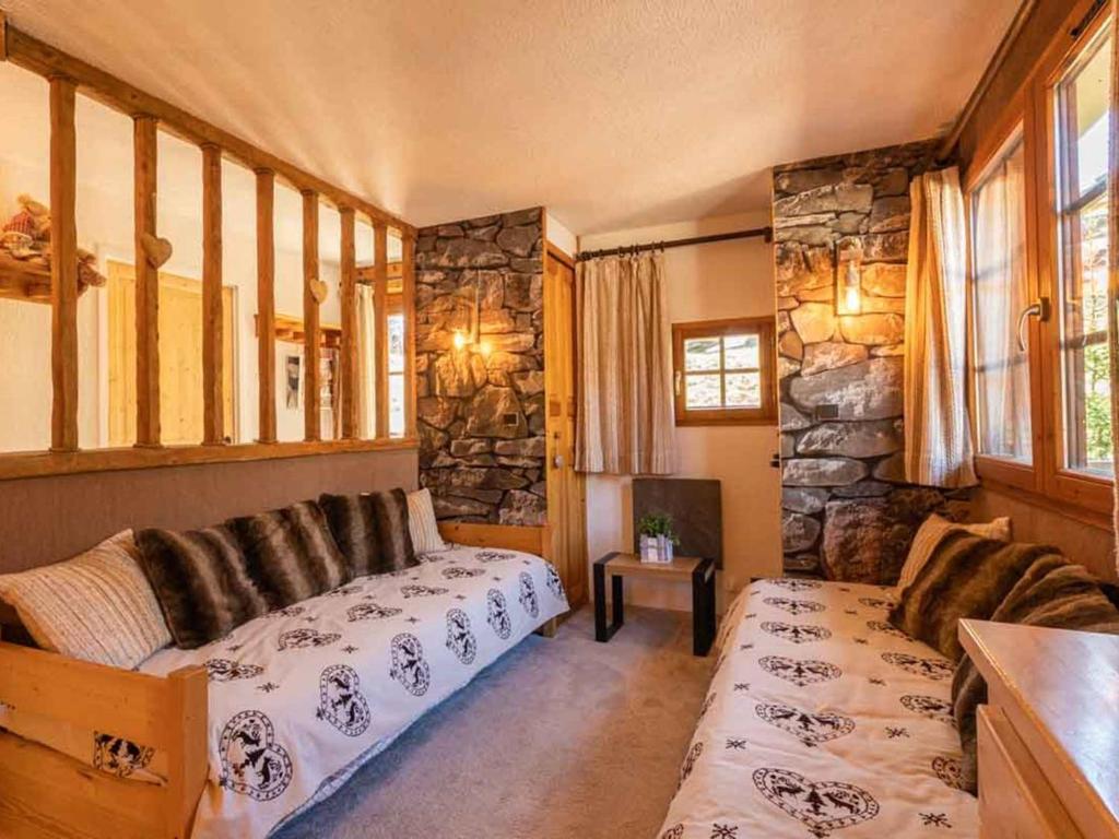 ein Wohnzimmer mit einem Bett und einer Steinmauer in der Unterkunft Charmant 2 pièces à Valmorel avec balcon, linge de lit et ménage inclus, 4 pers. - FR-1-291-879 in Valmorel