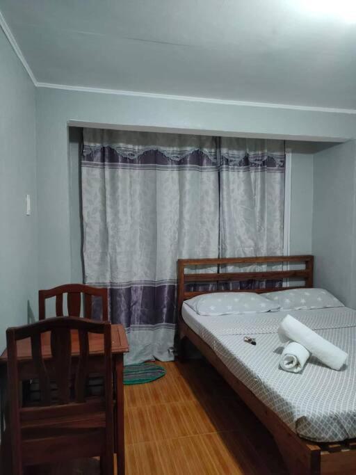 a bedroom with a bed and two chairs and a window at Cardo's Front Beach Room in General Luna