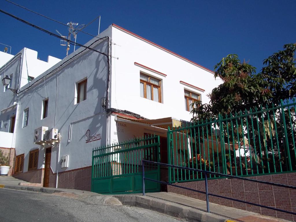 a white building with a green fence in front of it at Pension Eva in Puerto de Mogán