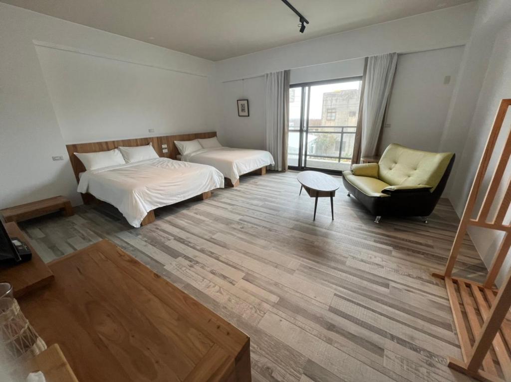 HuxiにあるWutong Homestayのベッド2台、ソファ、椅子が備わる客室です。