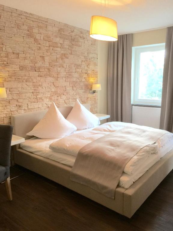 1 dormitorio con 1 cama grande y pared de ladrillo en Hotel Achilles en Kirkel