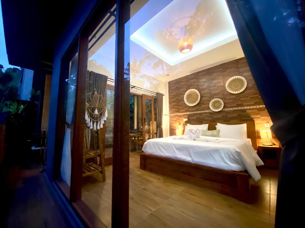 a bedroom with a bed and a large window at Ayu Homestay in Ubud