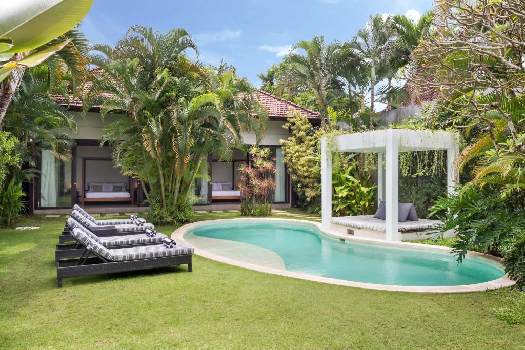a pool with two lounge chairs and a gazebo at Villa Alice in Seminyak