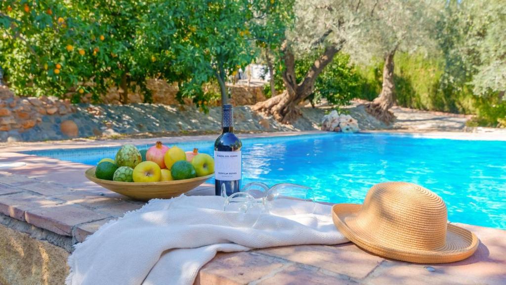 una bottiglia di vino e un cesto di frutta accanto alla piscina di Cortijo los Chinos Órgiva by Ruralidays a Órgiva
