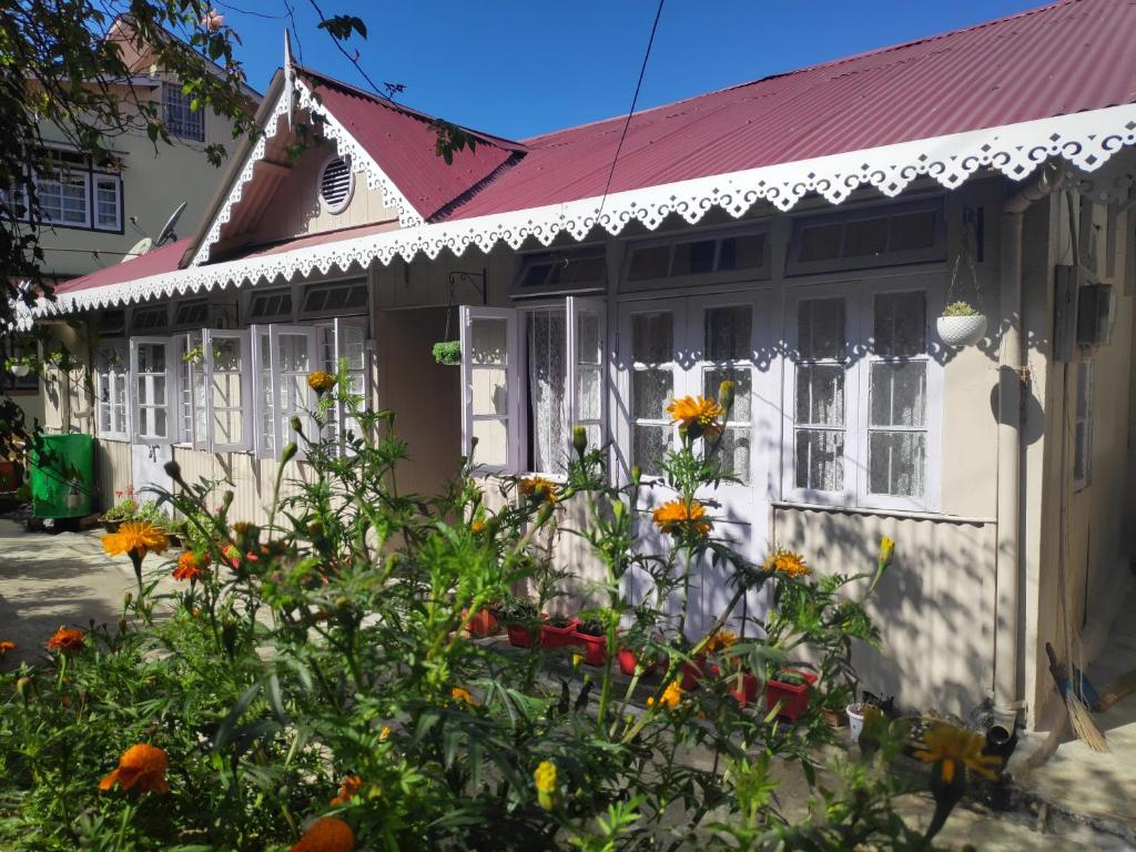 une maison blanche avec des fleurs devant elle dans l'établissement Darjeeling BnB, à Darjeeling