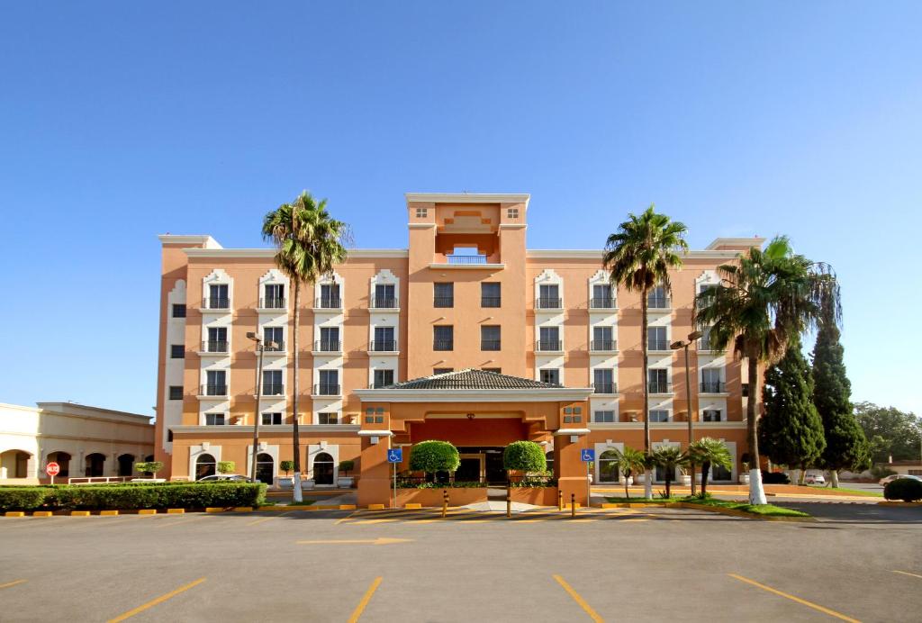 duży budynek z parkingiem przed nim w obiekcie iStay Hotel Ciudad Victoria w mieście Ciudad Victoria