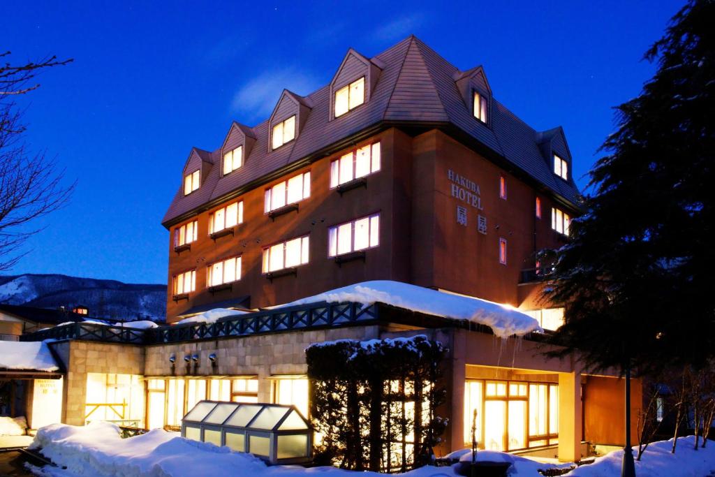 a large building with snow in front of it at Hakuba Hotel Ougiya in Hakuba