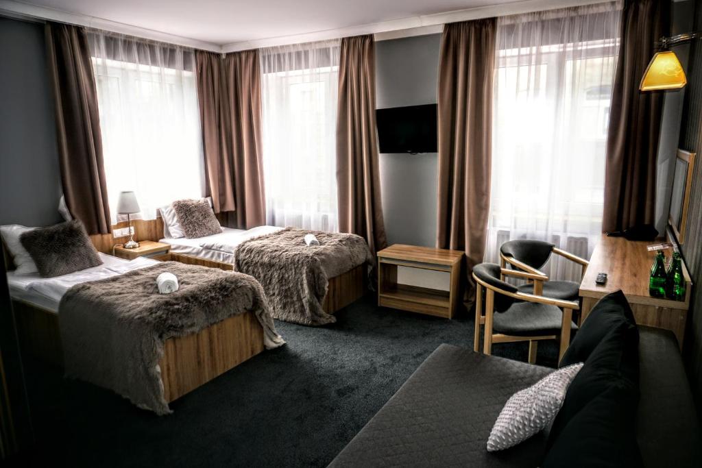 パビャニツェにあるAviator Hotel Restauracja & SPAのベッド2台と椅子があるホテルの部屋