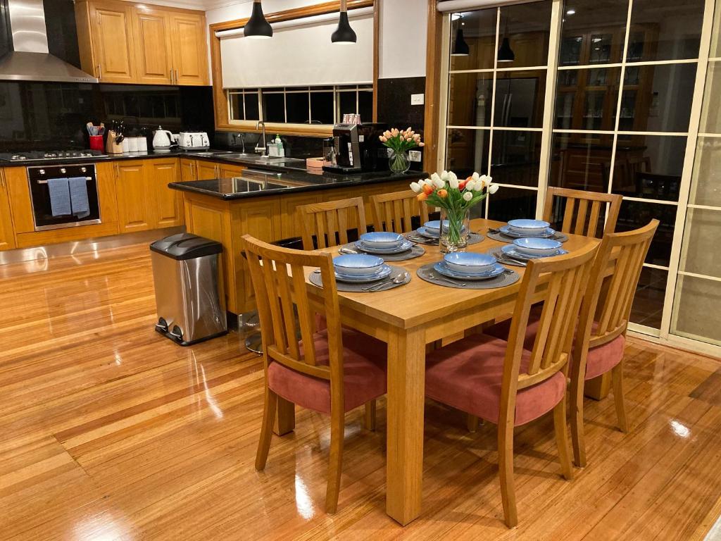 cocina con mesa y mesa de madera con sillas en Style/Comfort/Spacious 4 bedroom house plus study, en Melbourne