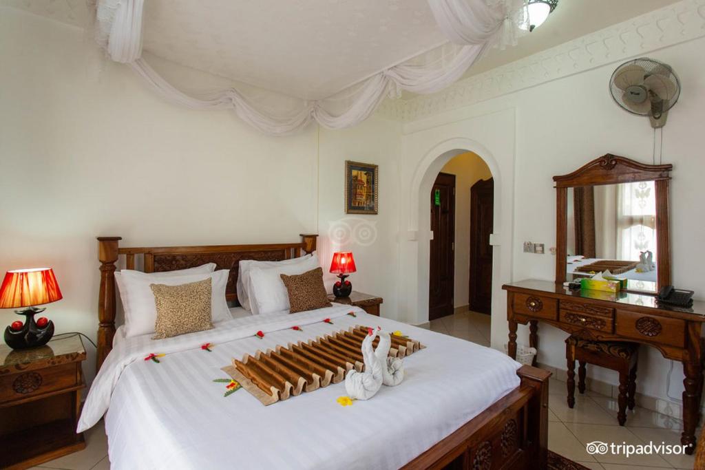 um quarto com uma grande cama branca e uma cabeceira em madeira em Al-Minar Hotel em Zanzibar City