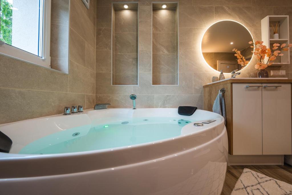 een groot wit bad in een badkamer met een spiegel bij Otepää Holiday Apartment with Jacuzzi in Otepää