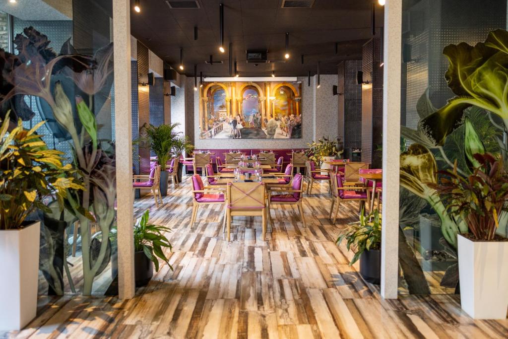 a restaurant with wooden floors and pink chairs and plants at Theory Hotel in Tbilisi City