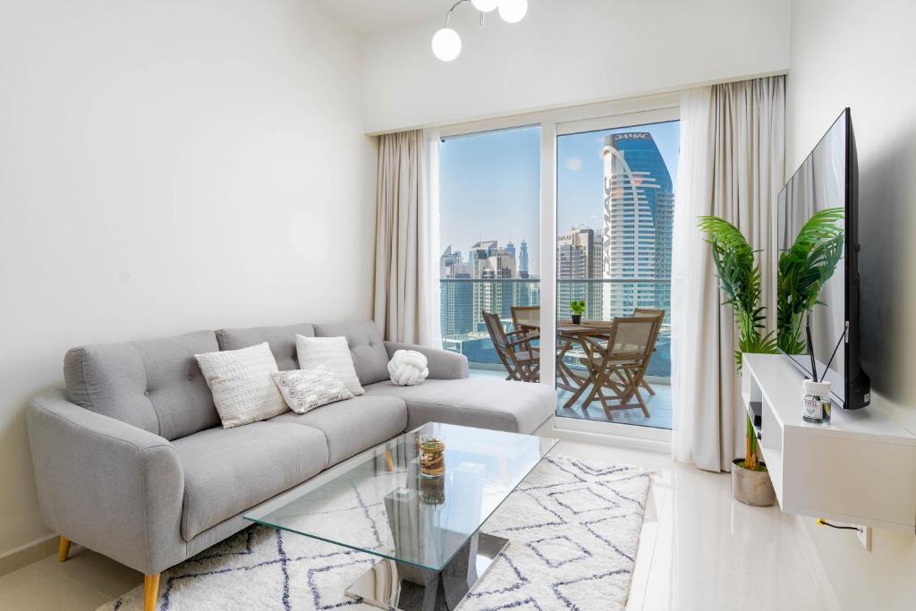 Delightful 2BR apartment at Reva Residences في دبي: غرفة معيشة مع أريكة وطاولة زجاجية