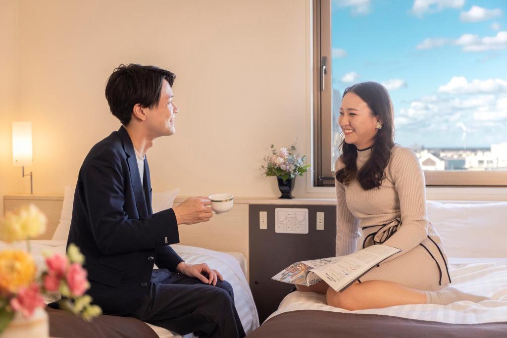 銚子市にある銚子プラザホテルのホテルの部屋のベッドに座る男女