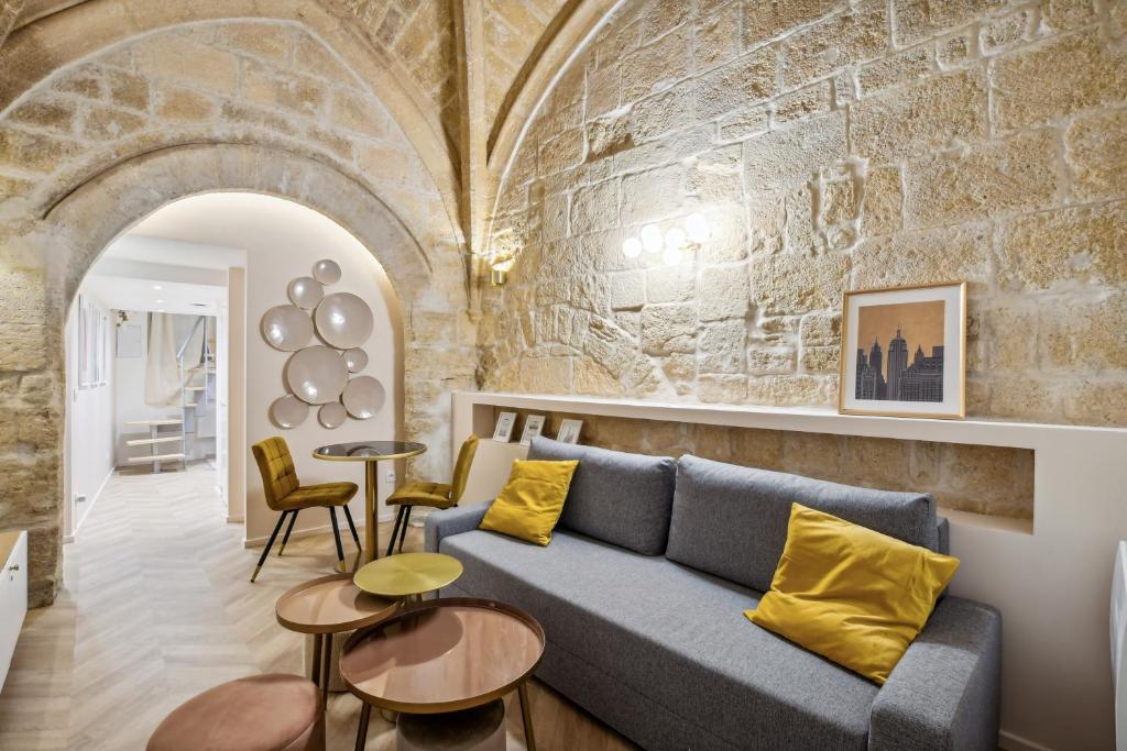 ein Wohnzimmer mit einem blauen Sofa und einer Steinmauer in der Unterkunft Hyper centre Écusson - Magnifique T1 au calme in Montpellier