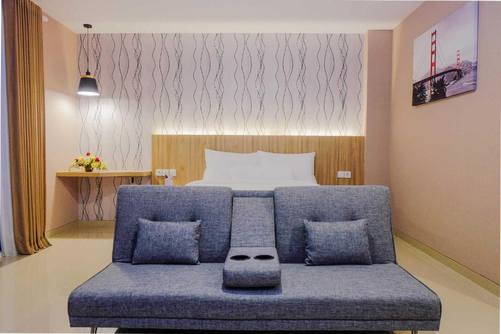1 dormitorio con 1 cama y 1 sofá azul con almohadas en Front One Hotel Sragen, en Sragen