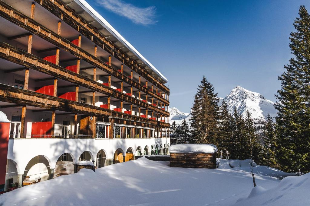 a building in the snow with a mountain in the background at Blatter's Arosa Hotel & Bella Vista SPA in Arosa