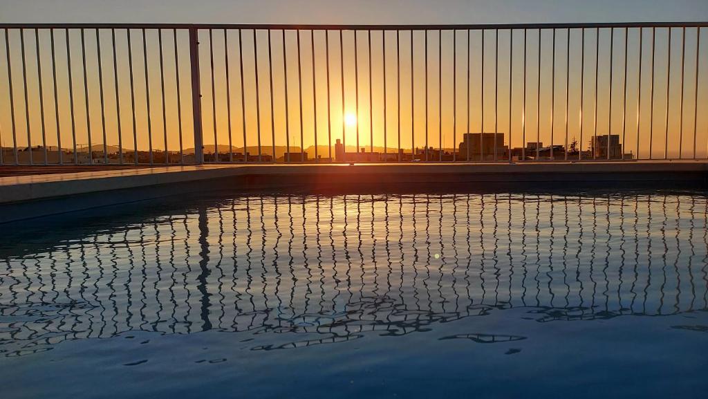 un bassin d'eau avec le coucher du soleil en arrière-plan dans l'établissement Penthouse, Sea Views and Private Roof Top Pool, à Il-Pergla