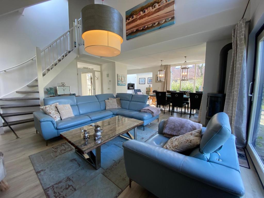 una sala de estar con sofás azules y una mesa. en Ferienhaus Ooghduyne 33 en Julianadorp